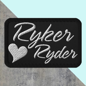 May include: Black embroidered patch with white lettering that reads "Ryker Ryder" with a white heart to the left of the text.