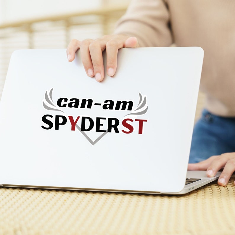 May include: A white laptop computer with the text "can-am SPYDERST" in black and gray lettering on the screen.