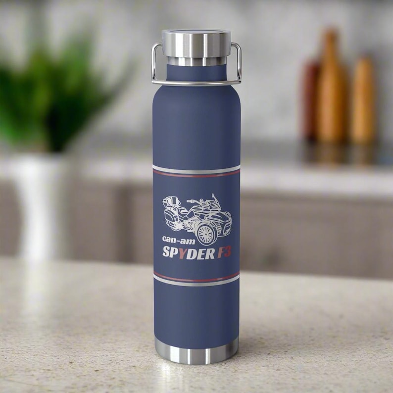 Pu&ograve; includere: Una borraccia blu navy con coperchio e manico argentati. La borraccia presenta una grafica bianca di un veicolo Can-Am Spyder F3, con la scritta "can-am SPYDER F3" sottostante. La borraccia &egrave; alta circa 25 cm.