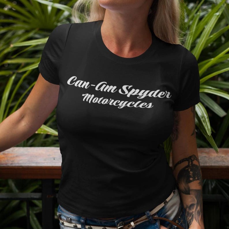 May include: Black crew neck t-shirt with the text "Can-Am Spyder Motorcycles" in white script. The shirt is short-sleeved and made of a soft material. The shirt is worn by a person.