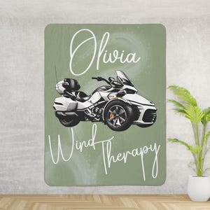 May include: A green and white throw blanket with the text "Olivia Wind Therapy" and a white motorcycle illustration.