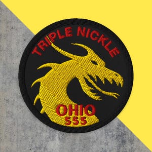 May include: Embroidered patch with a black background, featuring a yellow dragon design. The text "TRIPLE NICKLE" arches across the top in red, with "OHIO 555" at the bottom. The patch is circular.