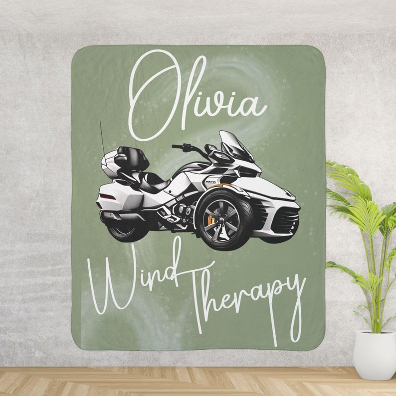 May include: A green and white throw blanket with a white motorcycle illustration and the text "Olivia Wind Therapy".