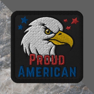 May include: A black embroidered patch with a white bald eagle head, red and blue stars, and the text "PROUD AMERICAN".