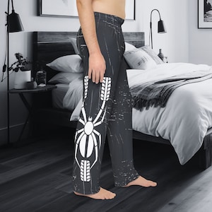 May include: Black and white pyjama trousers with a distressed look. The trousers feature a white spider design with tyre tread patterns on the legs.