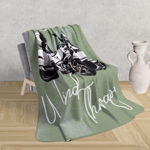 May include: Green fleece throw blanket featuring a white motorcycle illustration and the text "Wind Therapy" in white cursive.