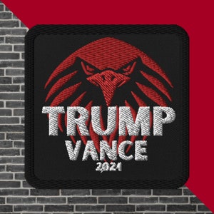 May include: Black square patch with a red eagle design and the words "TRUMP VANCE 2024" embroidered in white. The patch has a black border and is set against a brick wall and a red background.