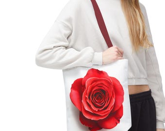 Op de afbeelding: Een witte tote bag met een rode roos bedrukt op de voorkant. De roos is in volle bloei en heeft een witte achtergrond.