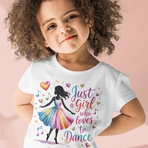May include: White t-shirt with a ballerina graphic and the text "Just a girl who loves to Dance". The design includes musical notes and hearts. The shirt is worn by a young child.