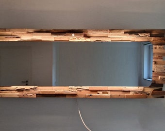 Peut inclure: Un miroir rectangulaire avec un cadre unique en bois de récupération. Le cadre est composé de morceaux de bois de différentes tailles, créant un aspect rustique et naturel. Le miroir est éclairé par une source de lumière derrière le cadre.
