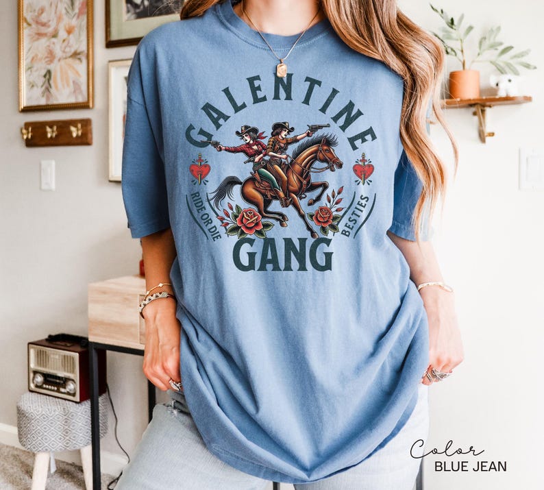 May include: Blue jean colored t-shirt with a graphic that reads "Galentine Gang". The graphic features two cowgirls riding a horse, surrounded by roses and hearts. The words "Ride or Die" and "Besties" are also included.