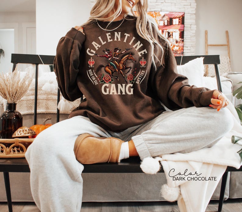 May include: Dark chocolate brown sweatshirt with the text "GALENTINE GANG" and a graphic of two women riding a horse. The sweatshirt also has the words "RIDE OR DIE" and "BESTIES".