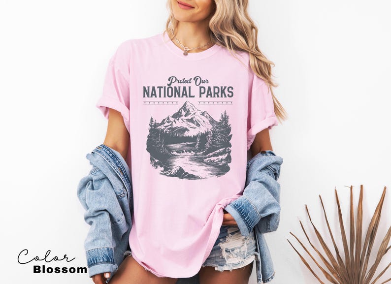 May include: A pink t-shirt with a graphic of a mountain range and a river. The text "Protect Our National Parks" is printed on the shirt.