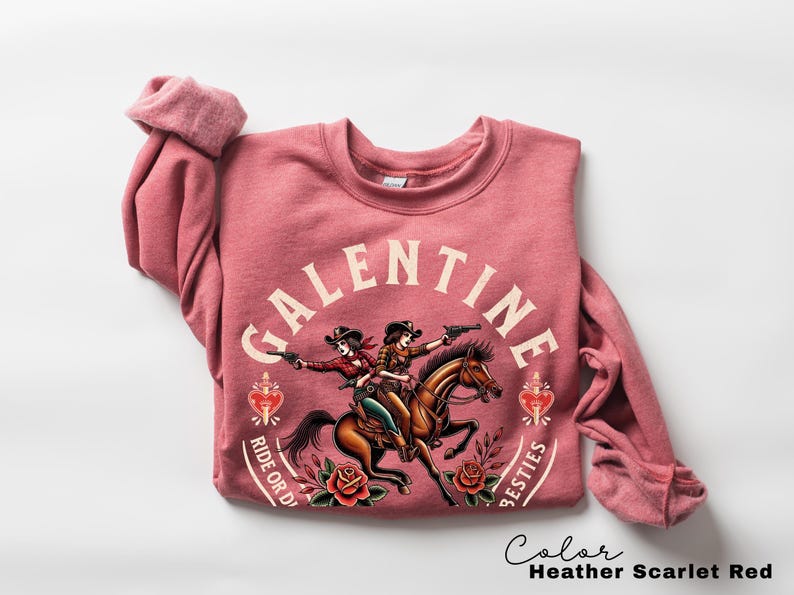 May include: Heather scarlet red sweatshirt with a graphic of two cowgirls on horseback, guns drawn. The word "Galentine" arches above the image, with "Ride or Die" and "Besties" below. Roses and hearts complete the design.