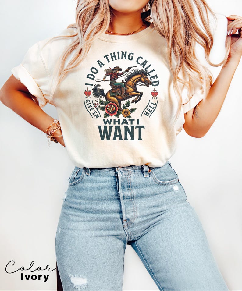 May include: Ivory t-shirt featuring a graphic of a woman riding a horse with the text "I do a thing called give 'em what I want".