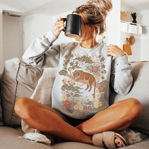 May include: A set of three ceramic mugs with a speckled, matte finish. The mugs are in shades of cream, light gray, and dark gray. Each mug has a simple, minimalist design and a rounded handle.