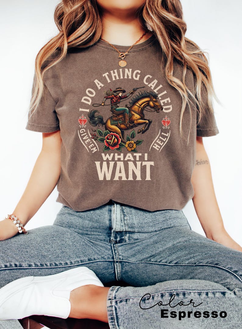 May include: A brown t-shirt featuring a graphic of a woman riding a horse. The text on the shirt reads "I do a thing called give 'em what I want".