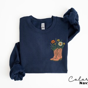 Puede incluir: Sudadera azul marino con un dise&ntilde;o floral con flores naranjas, amarillas y moradas en un par de botas de vaquero color melocot&oacute;n. El texto "Color Navy" est&aacute; escrito en una fuente cursiva en la parte inferior derecha.