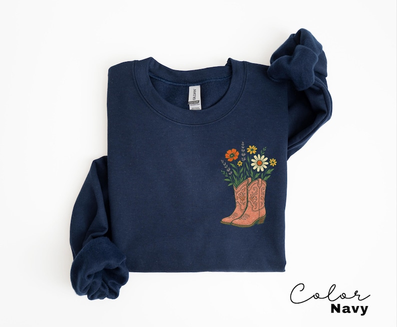 Puede incluir: Sudadera azul marino con un dise&ntilde;o floral con flores naranjas, amarillas y moradas en un par de botas de vaquero color melocot&oacute;n. El texto "Color Navy" est&aacute; escrito en una fuente cursiva en la parte inferior derecha.
