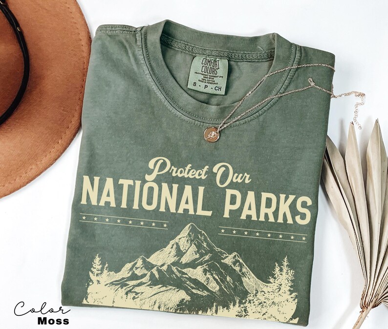 May include: A green t-shirt with the text "Protect Our National Parks" in yellow. The shirt features a graphic of mountains and trees in yellow.