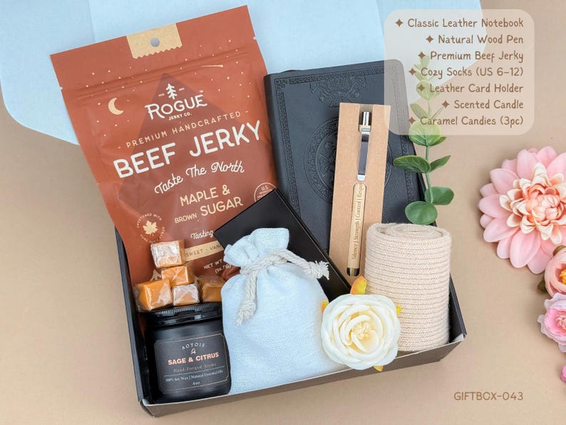Puede incluir: Una caja de regalo que contiene una bolsa de cecina Rogue de arce y az&uacute;car moreno, un cuaderno de cuero negro, un bol&iacute;grafo de madera natural, calcetines beige, un tarjetero de cuero, una vela de salvia y c&iacute;tricos y tres caramelos en una bolsa.