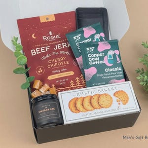 Puede incluir: Una caja de regalo que contiene una bolsa roja de carne seca Rogue Cherry Chipotle, dos paquetes de caf&eacute; de filtro Copper Cow Coffee color verde azulado, una vela negra Vintage Oak, galletas de caramelo salado Rustic Bakery y una cartera negra.