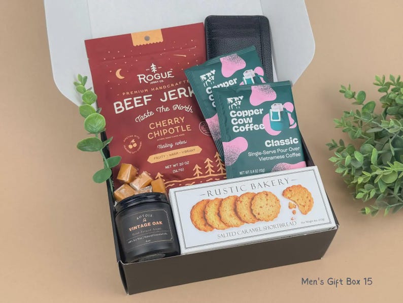 Puede incluir: Una caja de regalo que contiene una bolsa roja de carne seca Rogue Cherry Chipotle, dos paquetes de caf&eacute; de filtro Copper Cow Coffee color verde azulado, una vela negra Vintage Oak, galletas de caramelo salado Rustic Bakery y una cartera negra.