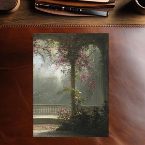 May include: An artistic print of a garden scene with a stone balustrade and a tree adorned with pink flowers. The print is set on a brown leather desk blotter, with a pen, pen holder, and a cup of coffee in the background.