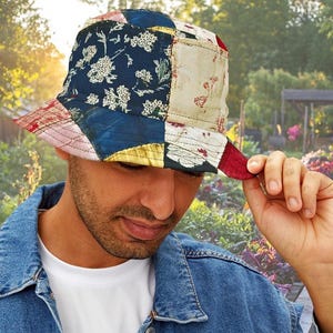 May include: A white ceramic mug with a black handle and the text "But First, Coffee" in a bold, black font. The mug is set against a blurred background, suggesting a cozy setting.