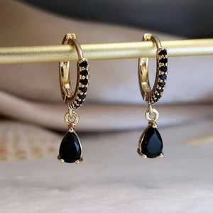 a pair of black and gold earrings on a stick