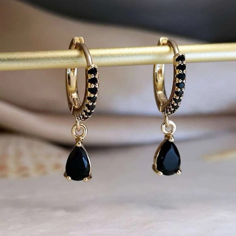 a pair of black and gold earrings on a stick