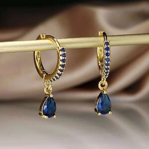 a pair of blue earrings sitting on top of a wooden stick