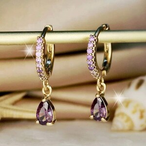 a pair of earrings with pink and purple stones