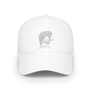 May include: White baseball cap with a black and white line drawing of a man's face on the front. The man is depicted with a cigarette in his mouth.