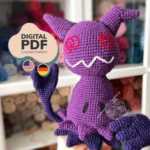 May include: A purple crochet doll with a unique design, featuring horns, rose-shaped eyes, and a jagged white mouth. The doll has a tail and hand-like appendages. The image includes text that says "DIGITAL PDF Crochet Pattern".