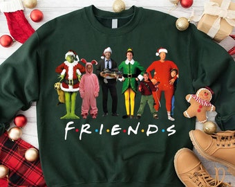 Puede incluir: Una sudadera verde oscuro con un gráfico de personajes disfrazados de figuras de películas navideñas, con la palabra "FRIENDS" en blanco. Los personajes incluyen al Grinch y a Buddy the Elf. Ropa festiva de vacaciones.
