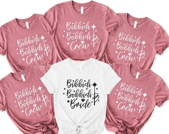 May include: Five t-shirts with the text "Bibbidi Bobbidi Boo" and a star and wand graphic. One shirt says "Bride" instead of "Crew". The shirts are in shades of pink and white.