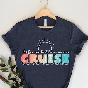 May include: A navy blue t-shirt with a rainbow colored graphic that says "Life is better on a cruise" with a sun above the text.