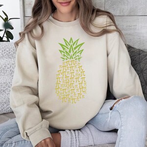 a woman sitting on a couch wearing a sweater with a pineapple on it