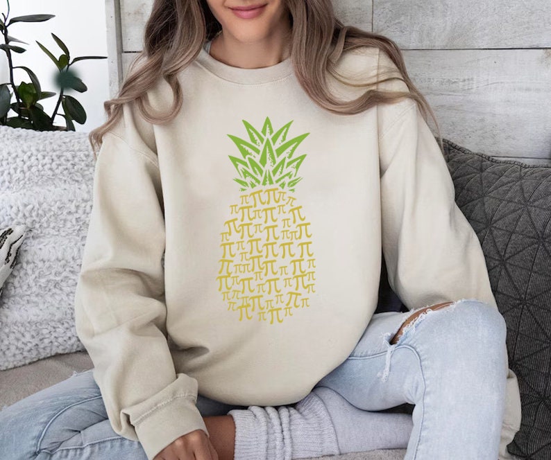 a woman sitting on a couch wearing a sweater with a pineapple on it