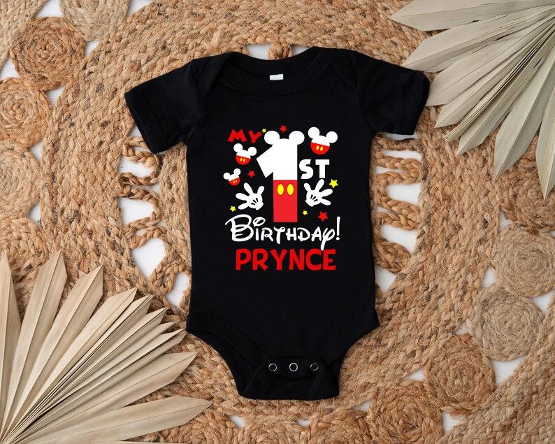 Puede incluir: Body negro con un gr&aacute;fico tem&aacute;tico de Mickey Mouse rojo y amarillo que dice "My 1st Birthday! Prynce".