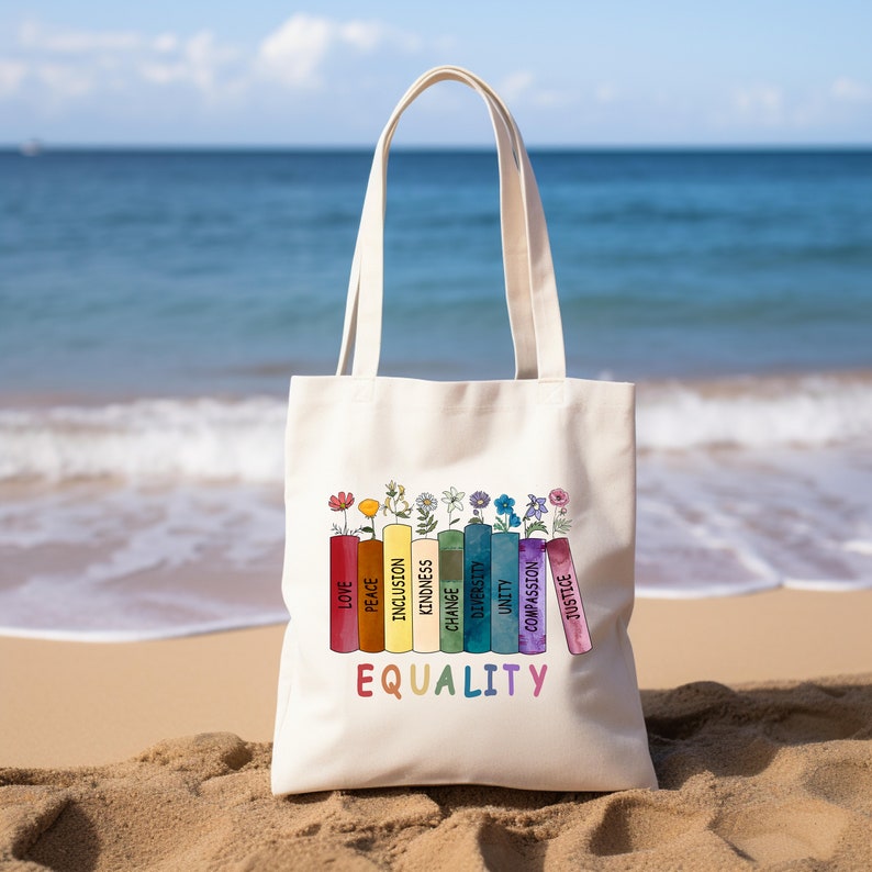 a tote bag sitting on a beach with the ocean in the background