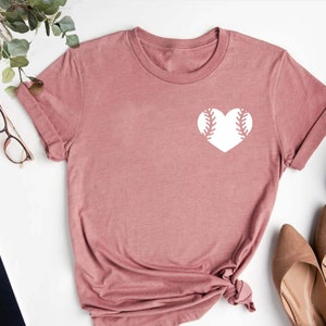 May include: A dusty rose t-shirt with a white baseball-shaped heart graphic.