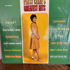 Op de afbeelding: Verzegelde vinylplaat van Patsy Cline's Greatest Hits. De albumhoes toont Patsy Cline in een mosterdkleurige jurk. Titels zijn onder meer "Crazy", "Sweet Dreams" en "She's Got You". Het album is van MCA Records.