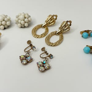 May include: Assortment of vintage clip-on earrings featuring blue, white, and light blue glass beads and rhinestones.