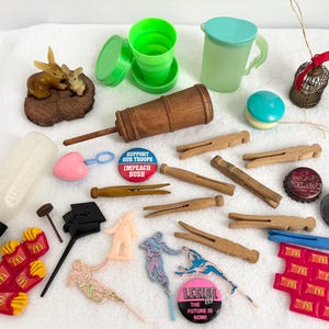 May include: A collection of various small objects, including a baby bottle, clothespins, a yo-yo, and a miniature birdcage. Other items include a brown wooden object, a green cup, and several small plastic figures. There are also several McDonald's french fry containers.