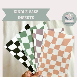 May include: Four different checkerboard patterned cardstock inserts for a Kindle case. The inserts are in black and white, green and white, purple and white, and peach and white. The text "KINDLE CASE INSERTS" is at the top of the image. The text "Cardstock insert for e-reader clear case **clear case not included**" is at the bottom of the image.