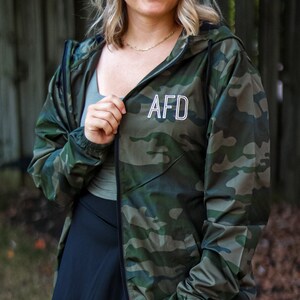 May include: A green and brown camouflage jacket with a zipper and a hood. The jacket has the letters "AFD" embroidered on the front.
