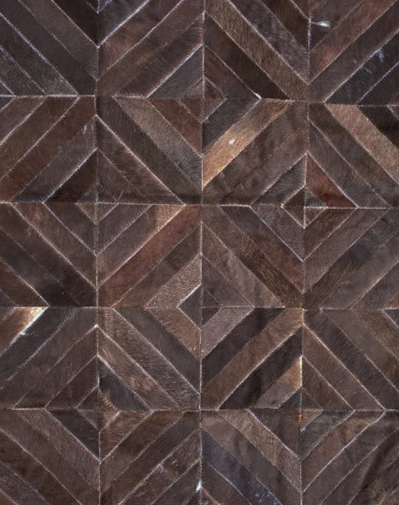 K&ouml;nnte beinhalten: Ein brauner Lederteppich mit einem geometrischen Muster aus Quadraten und Rauten. Der Teppich ist aus verschiedenen Braunt&ouml;nen gefertigt und hat einen rustikalen, Vintage-Look.