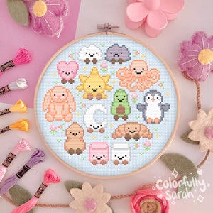 Puede incluir: Un aro de bordado azul con fondo blanco y un círculo de personajes de dibujos animados lindos. Los personajes incluyen una nube, una roca, un pulpo, un sol, un aguacate, un pingüino, una luna creciente, un croissant, un conejito, un malvavisco y un oso marrón. El aro está rodeado de hilo de bordar de colores.